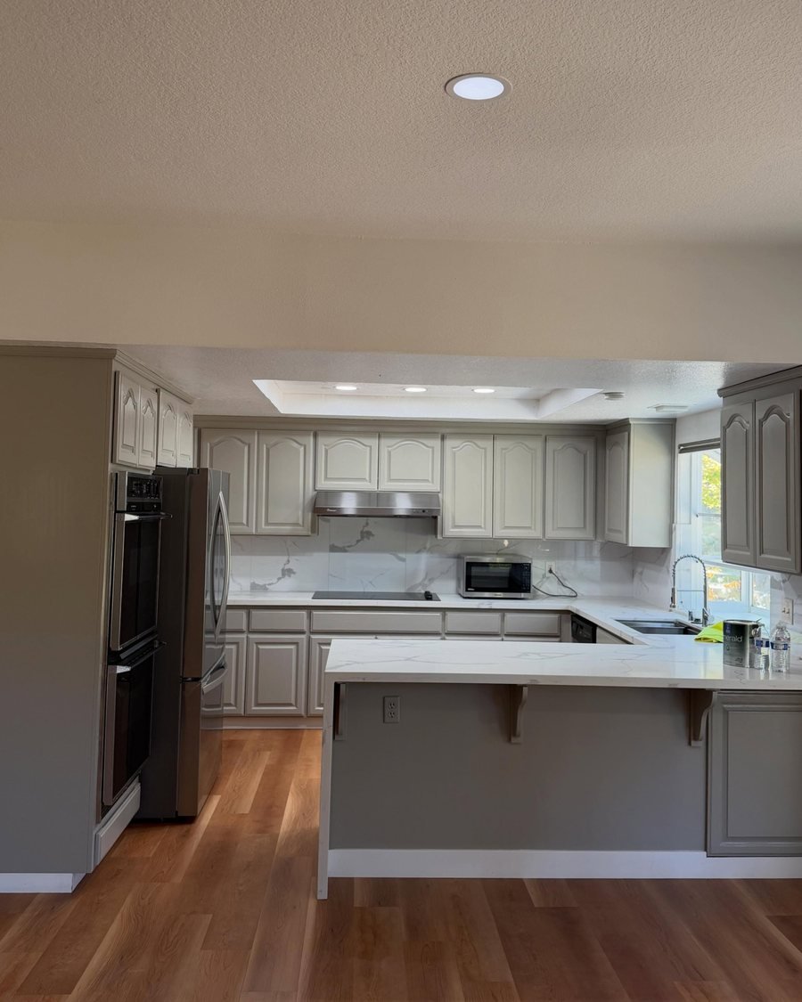 After: the same kitchen with the cabinets, peninsula and tall oven cabinet painted gray