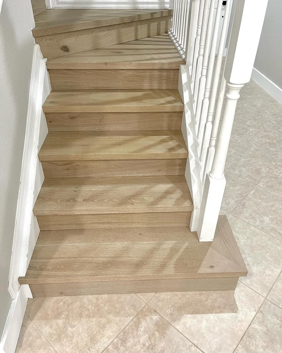 After: the same staircase with light oak-look treads and risers and a matching bottom step