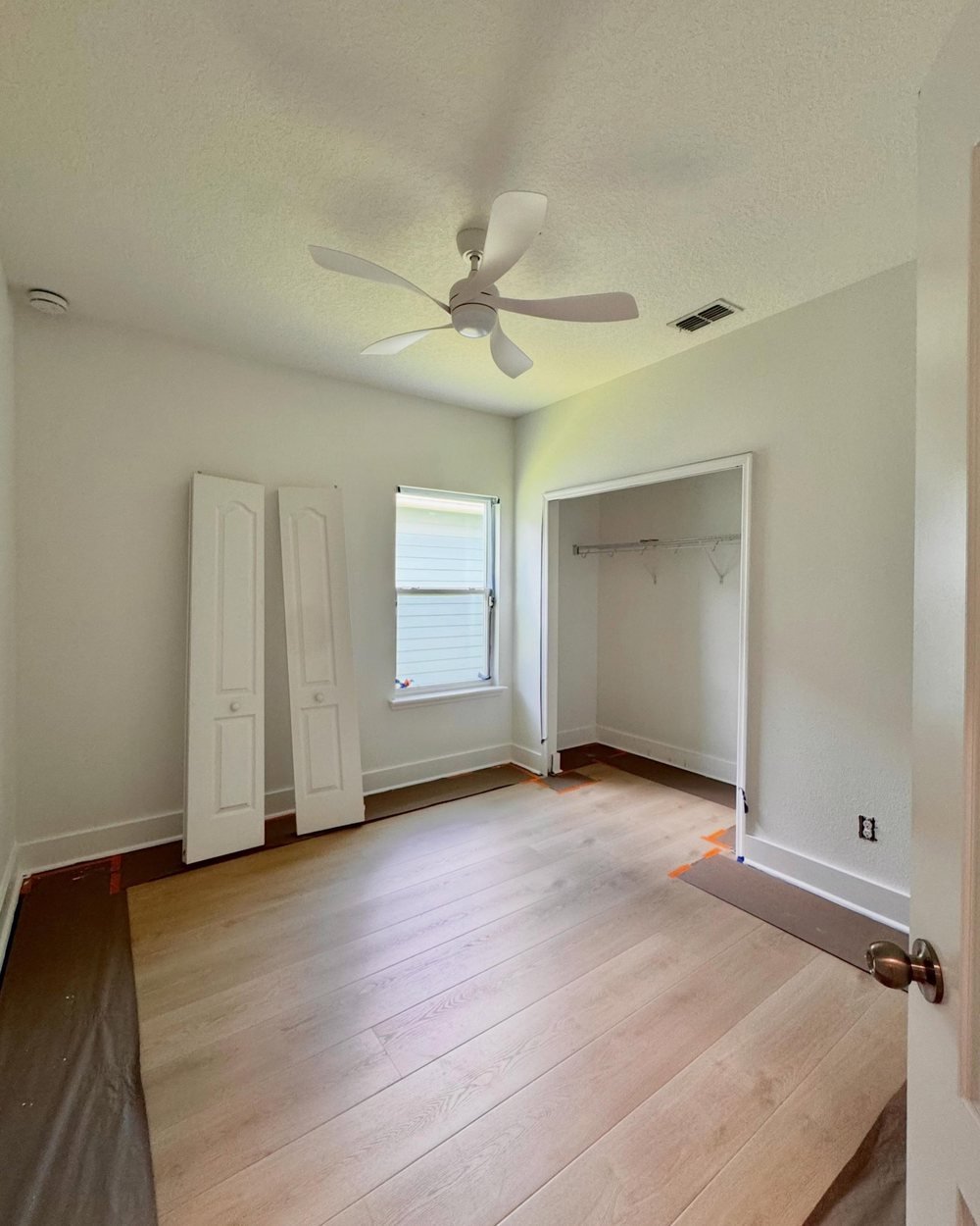 Bedroom with fresh white walls and trim, closet doors off for painting