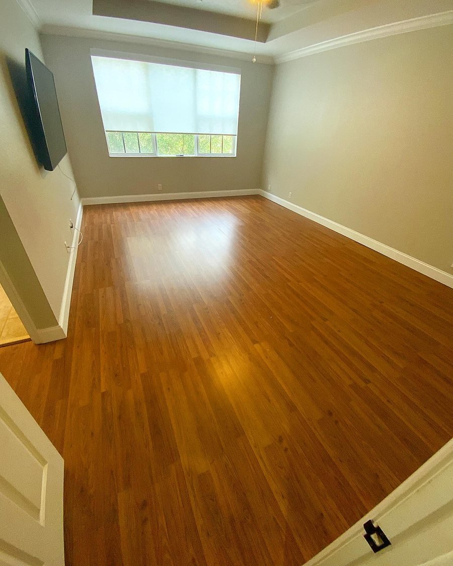 Before: empty bedroom with orange-toned laminate flooring and gray walls