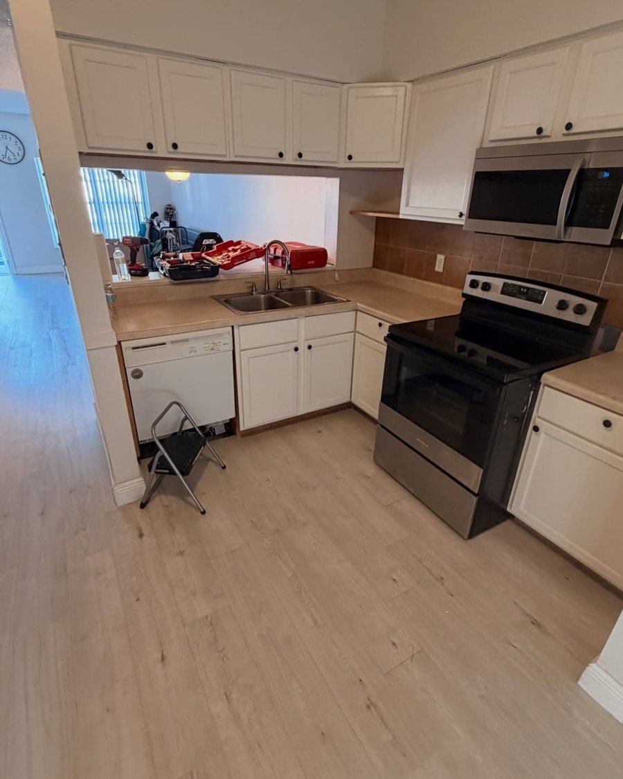 Before: small kitchen with older white cabinets, beige laminate countertops, a brown tile backsplash and a white dishwasher