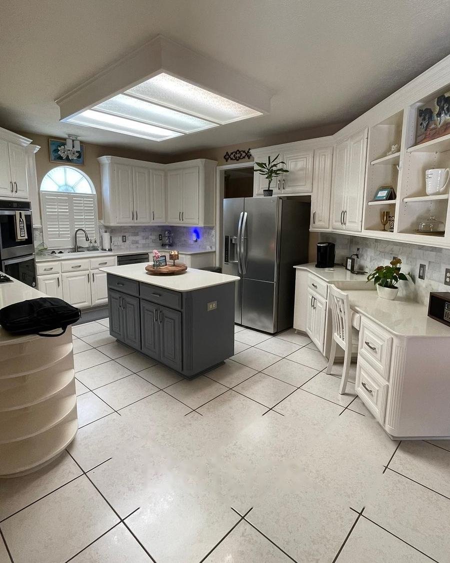 Before: white kitchen with a fluorescent ceiling light box, white tile floors and solid white countertops