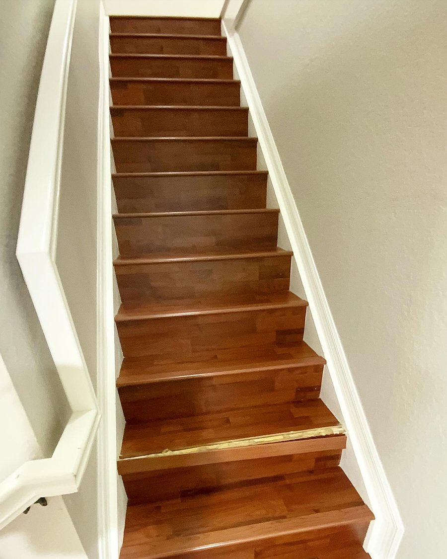 Before: straight staircase with red-brown laminate treads and risers