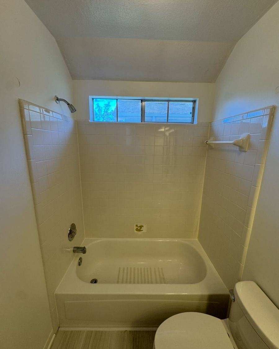 Before: tub surround with small cream square tile and chrome fixtures