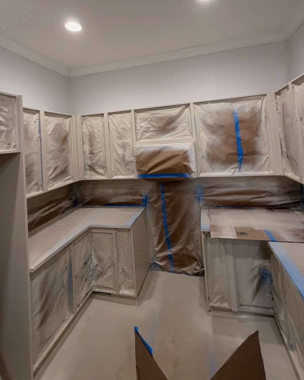 Cabinet frames after spraying, with doors off and counters still covered
