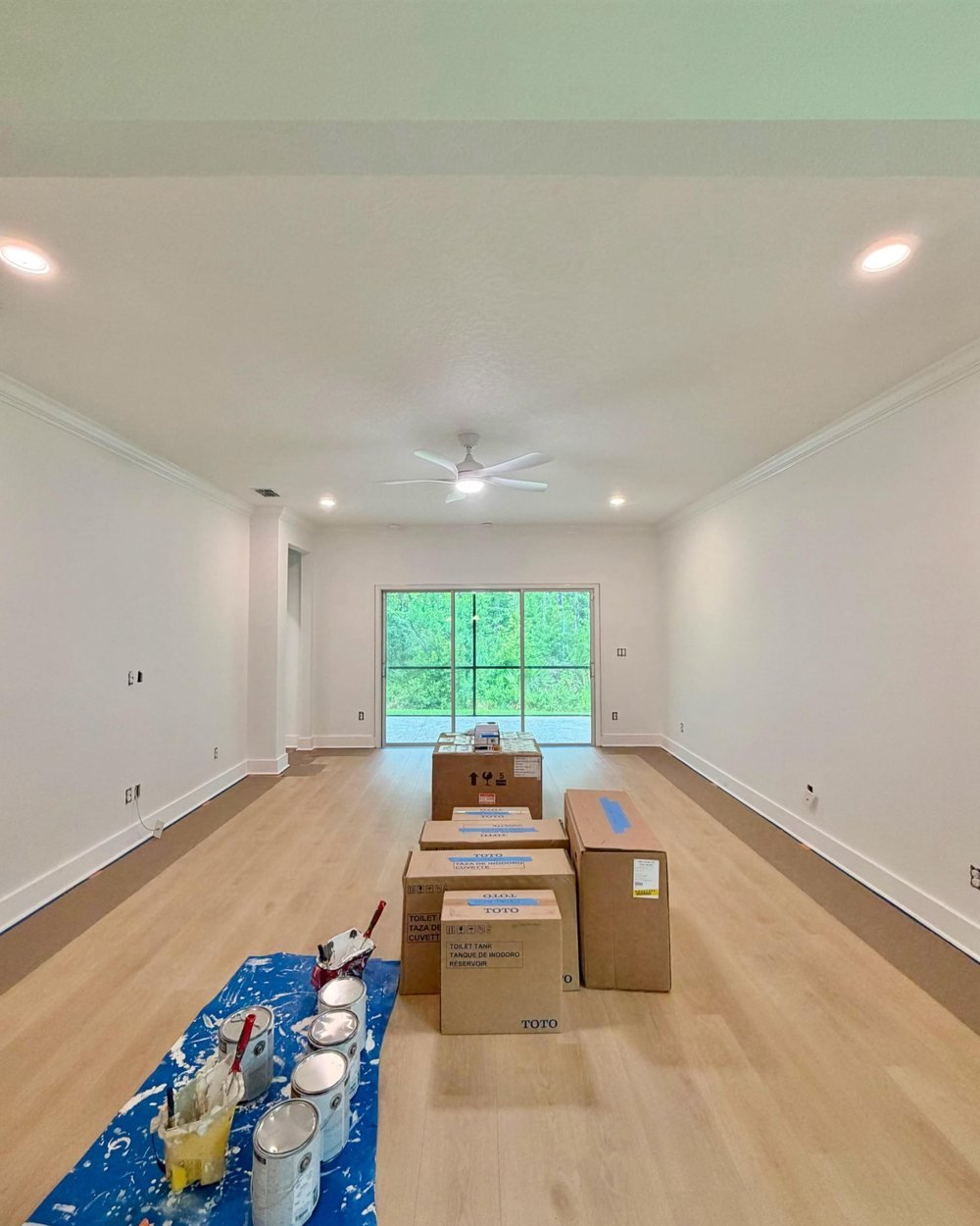 Great room with freshly painted white walls, crown molding and the floor edges protected