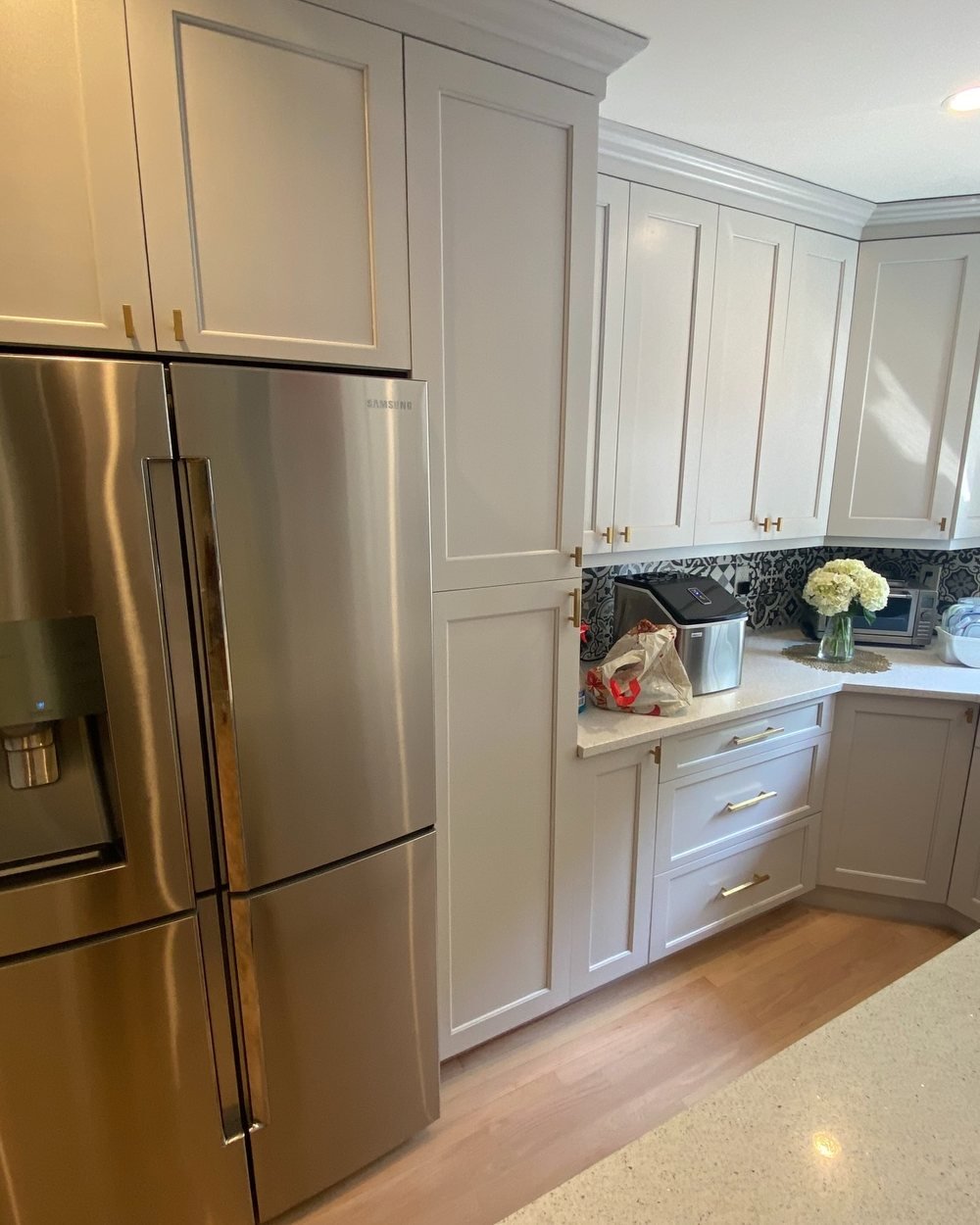 Gray shaker cabinets with brass pulls, crown molding and a patterned tile backsplash