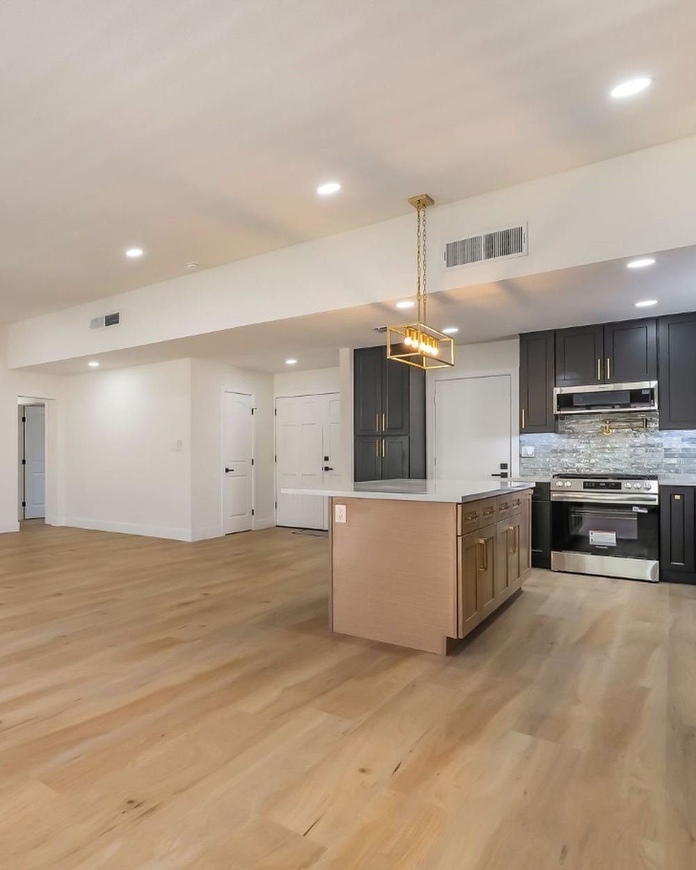 Finished open-concept kitchen remodel with an island, pendant lighting and light wood floors