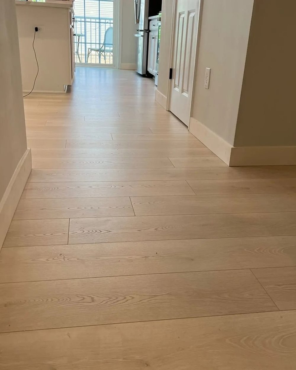 Hallway with light wood-look plank flooring and white baseboards