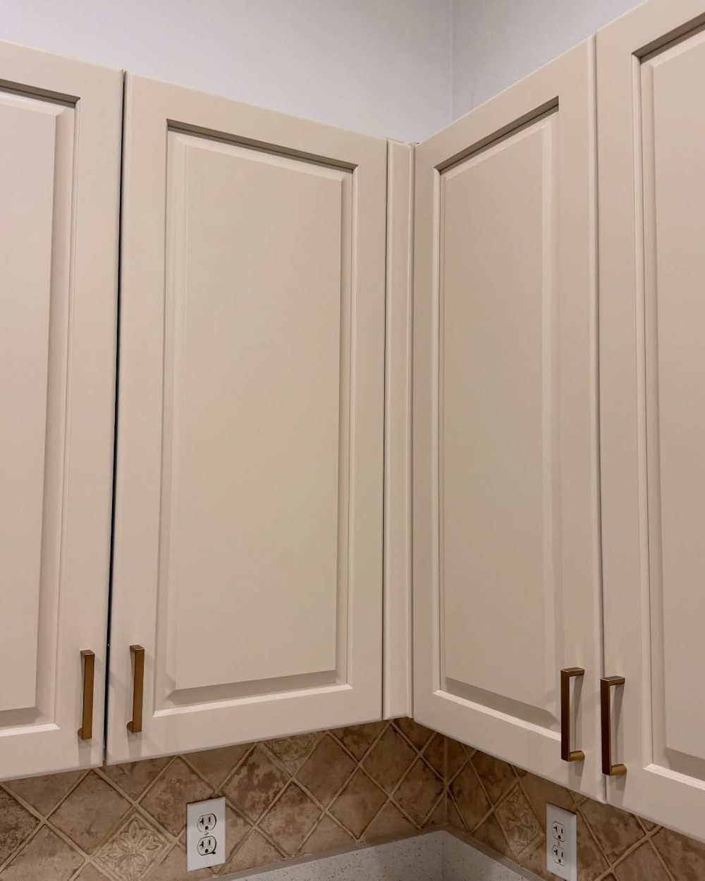 Close-up of painted cream cabinet doors with brass pulls