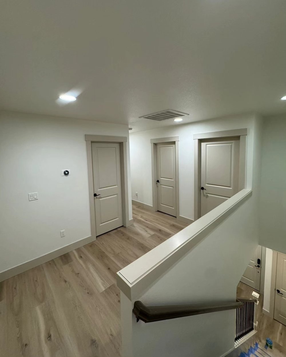 Upstairs landing with white walls and three greige painted doors