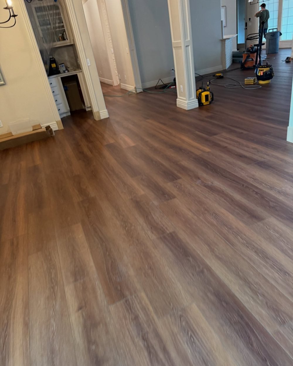 Plank flooring installation in progress, with tools and a vacuum still on site