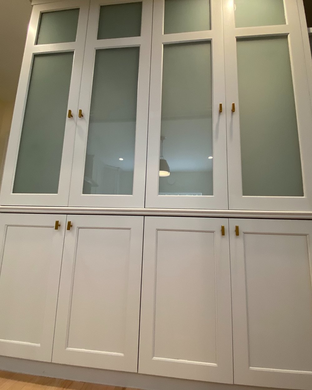 White built-in cabinet with frosted glass upper doors and brass knobs