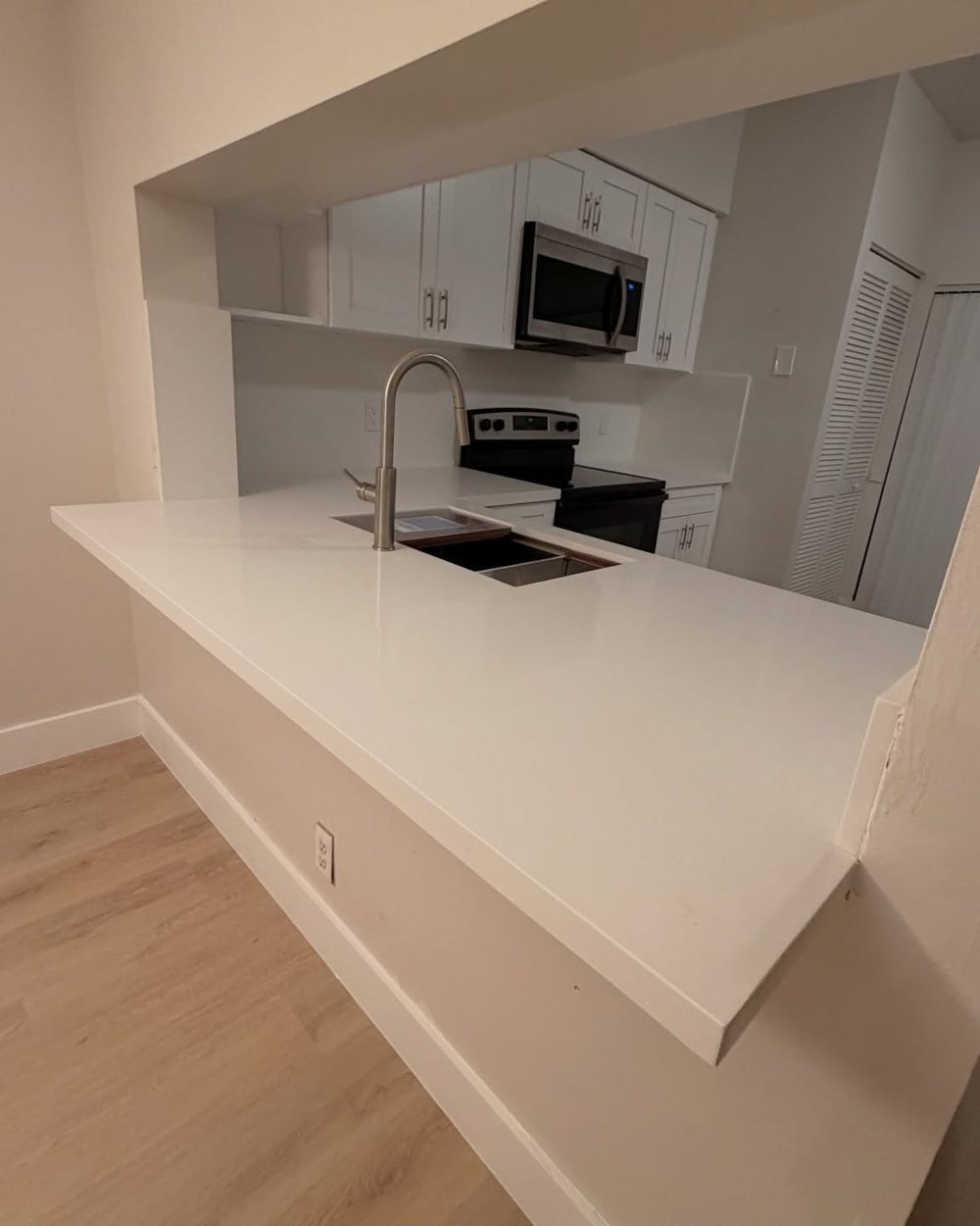 White countertop extending through a pass-through opening as a breakfast bar