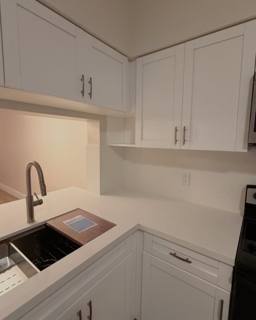 White countertop with an undermount workstation sink and white shaker cabinets