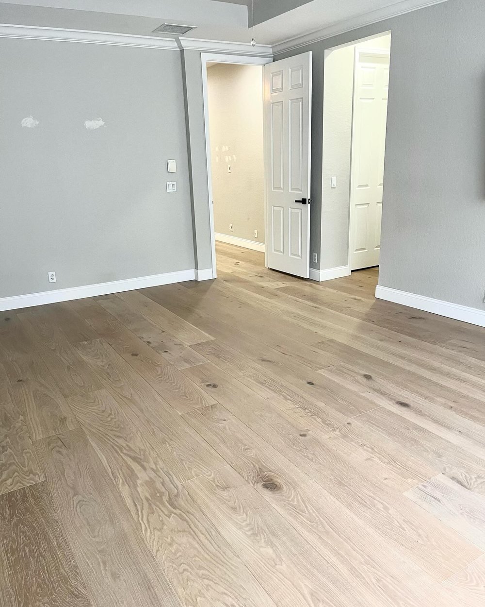 Bedroom with light wide-plank flooring and gray walls, looking toward the door