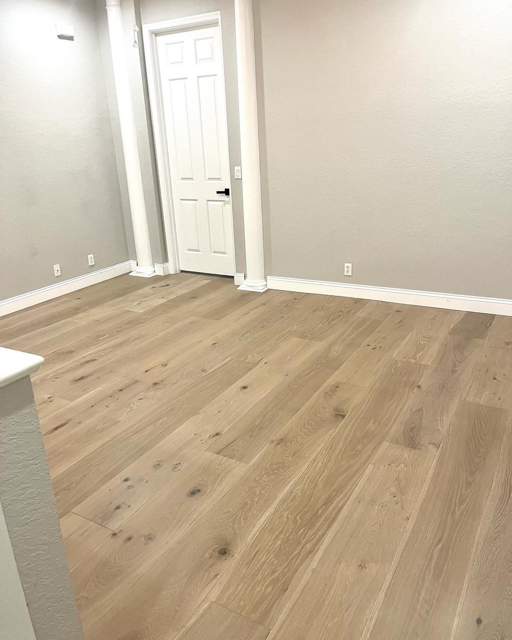 Upstairs landing with light wide-plank flooring and white columns